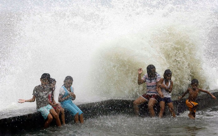 Trẻ em nghịch sóng trên đê biển ở Manila.