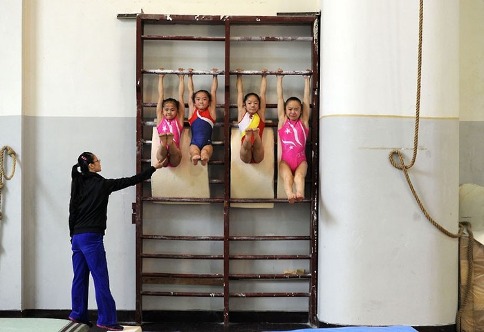 Các bé gái tại một trung tâm huấn luyện thể thao đặc biệt ở Hợp Phì, Trung Quốc. Các vận động viên thể dục dụng cụ tiềm năng phải tập luyện theo một chương trình khắc nghiệt mới có thể giành được huy chương vàng. Những đứa trẻ này phải tập luyện 8 tiếng mỗi ngày và 6 ngày mỗi tuần.