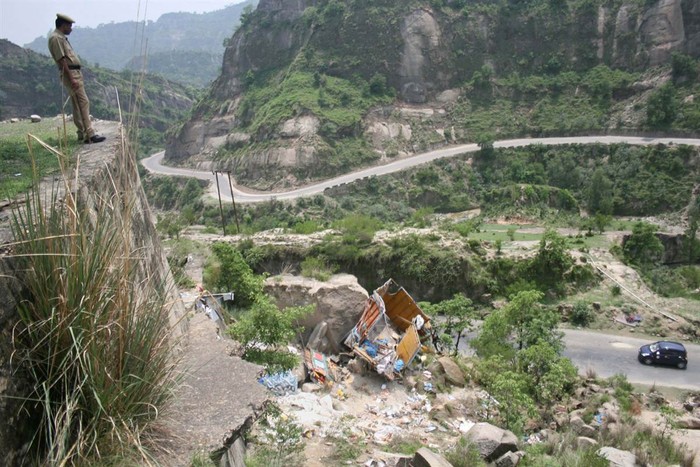 Cảnh sát nhìn đống đổ nát của một chiếc xe tải chở 16 người hành hương Hindu bị rơi xuống hẻm núi sâu gần Jammu, Ấn Độ ngày 27/7.