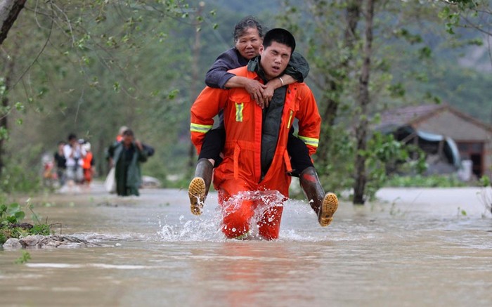 Một nhân viên cứu hộ đưa một người dân lớn tuổi tới khu vực an toàn ở Đài Châu, Chiết Giang.
