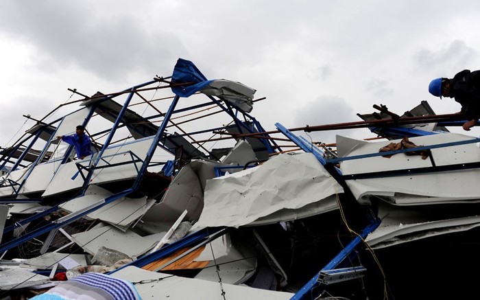 Công nhân đang cố gắng thu thập những thứ còn có thể tái sử dụng tại đống đổ nát của một tòa nhà bị bão quật đổ ở Hợp Phố, Tượng Sơn, Chiết Giang.