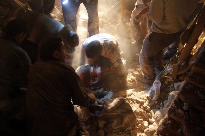 Một người Iran bị thương trong động đất đang được giúp đỡ đưa ra khỏi đống đổ nát.