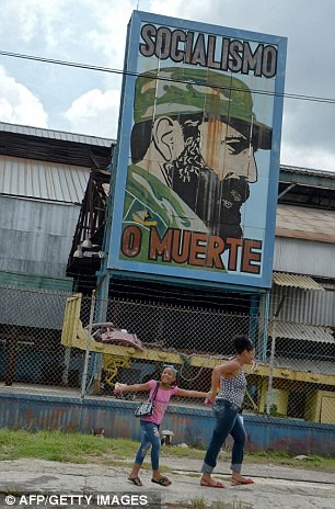 Trẻ em cùng mẹ đi qua một bức chân dung của Chủ tịch Fidel Castro.