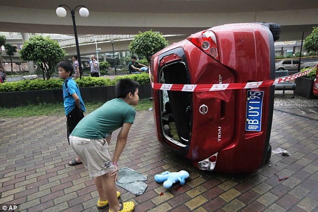 Một cậu bé đứng xem chiếc xe hơi Nhật bị những người biểu tình lật đổ và đập phá.
