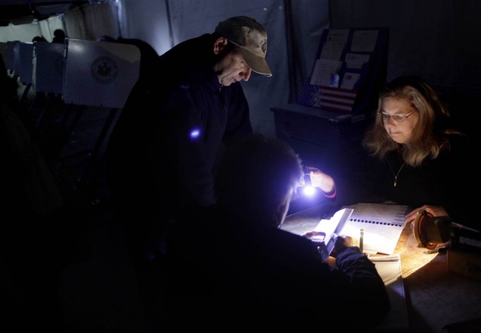 Lisa Amico (phải) giúp các cử tri bỏ phiếu sớm trong điều kiện mất điện do ảnh hưởng của bão Sandy tại một địa điểm bỏ phiếu ở Midland Beach Staten Island, New York, Mỹ ngày 6/11.
