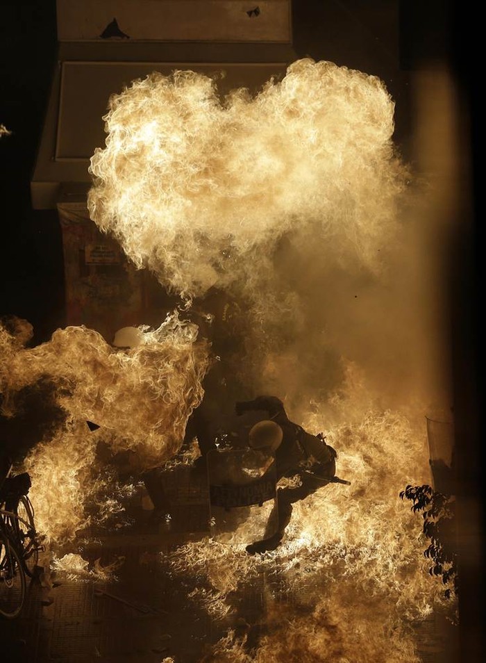 Một sĩ quan cảnh sát chống bạo động bị nhấn chìm bởi ngọn lửa do người biểu tình ném bom xăng trước tòa nhà quốc hội ở Athens, Hy Lạp hôm 7/11.