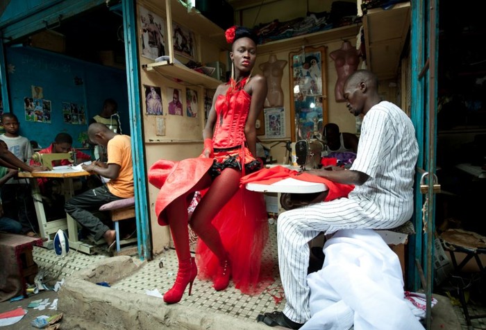 Một người mẫu đứng trước gian hàng may mặc ở trung tâm Dakar, Senegal trong tuần lễ thời trang Dakar. Cô mặc chiếc váy của nhà thiết kế người Senegal sống tại Mỹ Yolande Ngom Mancini. Ảnh: Vincent Boisot.
