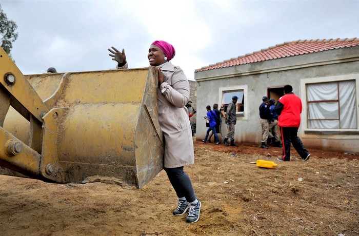 Một phụ nữ đang cố ngăn chiếc xe ủi đất phá hủy ngôi nhà xây dựng bất hợp pháp của cô tại tây nam Johannesburg, Nam Phi hôm 9/11.