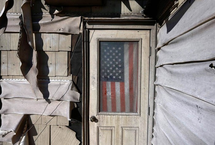 Lá quốc kỳ treo phía trước cửa một ngôi nhà bị hư hỏng nặng do bão Sandy tại Breezy Queens, Ne York hôm 14/11.