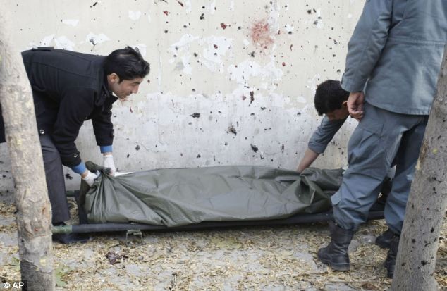 Các nhân viên an ninh Afghanistan gói xác một nạn nhân tại hiện trường vụ nổ.