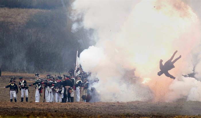 Một hình nộm bị bắn tung lên không trung giữa những người đàn ông mặc quân phục Nga và Pháp tham gia tái hiện trận chiến 1812 của Berezina tại Bryli, Belarus ngày 24/11.