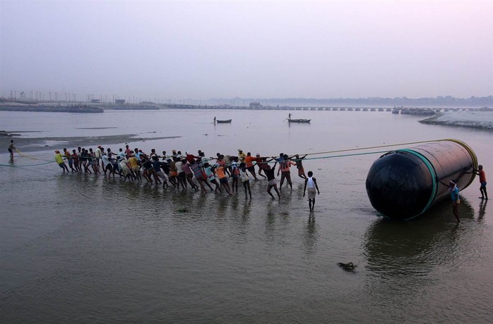 Những người lao động Ấn Độ kéo một chiếc phao trên sông Hằng để chuẩn bị cho lễ hội Kumbh Mela, nơi hàng triệu người sẽ đổ về tắm trong dòng nước thiêng, ở Allahabad ngày 21/11.