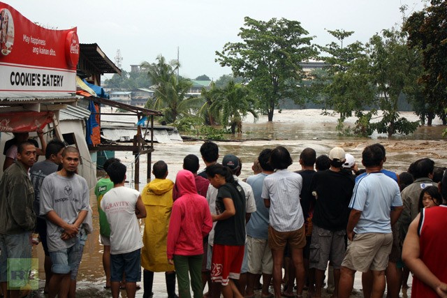 Người dân sống tại thành phố Cagayan de Oro, nam Mindanao đứng nhìn dòng nước nhấn chìm nhà của họ hôm 4/12.