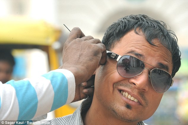 Một người đàn ông Ấn Độ sảng khoái khi được làm sạch tai trên phố.