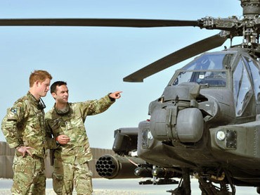 Hoàng tử Harry (trái) bên cạnh chiếc Apache tại Trại Bastion ở Afghanistan.