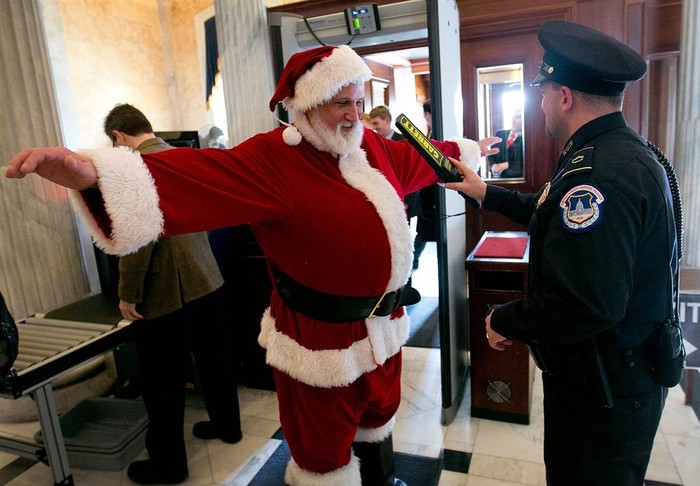 Cảnh sát Capitol Hill kiểm tra một người đàn ông ăn mặc như ông già tuyết bằng máy dò kim loại trước cửa Tòa nhà Quốc hội tại Washington, Mỹ ngày 12/12.