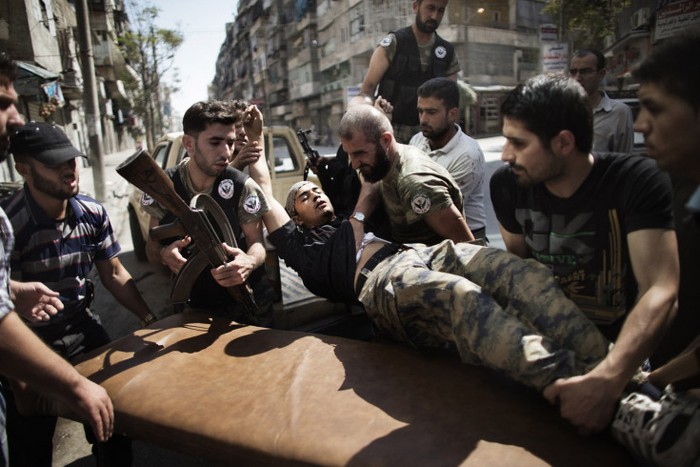 Phiến quân Syria giúp một đồng đội bị thương, người sống sót sau một cuộc giao đấu với Quân đội Syria bên ngoài một bệnh viện ở Aleppo tháng 9/2012.
