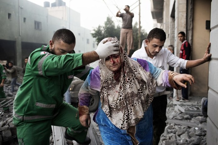 Một phụ nữ Palestine được giúp đỡ ra khỏi đống đổ náy của ngôi nhà bị phá hủy trong cuộc không kích của Israel nhằm vào một trung tâm thể thao gần đó tại thành phố Gaza ngày 19/11.