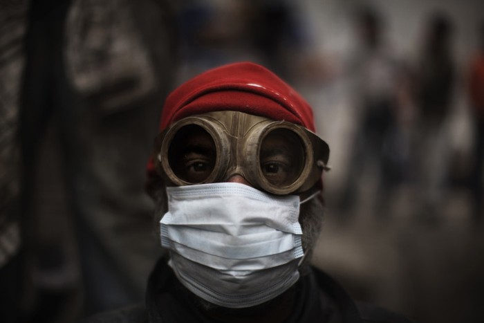Một người biểu tình Ai Cập sử dụng kính bảo hộ và mặt nạ để bảo vệ mình khỏi hơi cay được bắn ra bởi cảnh sát chống bạo động trong cuộc đối đầu bên ngoài trụ sở an ninh của Cairo tháng 2/2012.