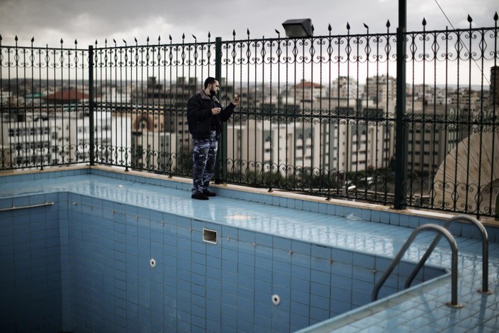 Một cảnh sát Palestine chụp ảnh bằng điện thoại từ tầng thượng của một tòa nhà, nơi có thể nhìn ra địa điểm diễn ra cuộc biểu tình tại thành phố Gaza hôm 8/12. Hơn 100.000 người Palestine tập trung cho các cuộc biểu tình, đánh dấu kỷ niệm 25 năm thành lập Hamas.