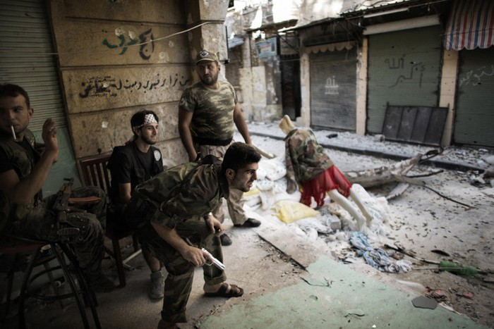 Phiến quân Syria ngồi cạnh một tay súng giả ở Aleppo tháng 9/2012.