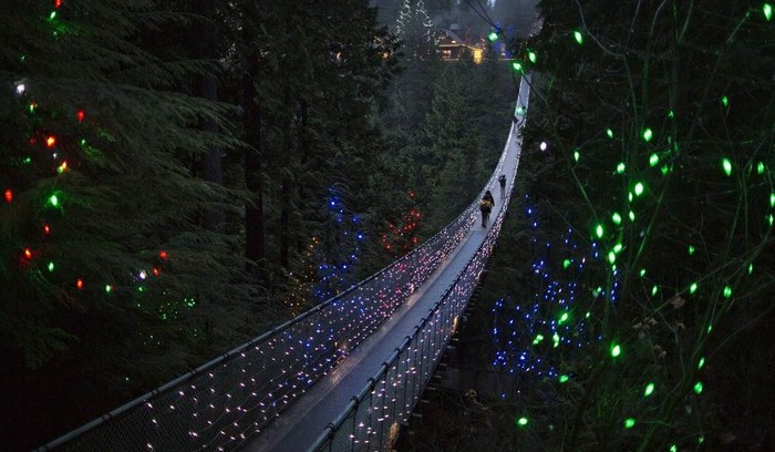 Du khách đi ngang qua cầu treo Capilano được trang trí đèn Giáng sinh ở Bắc Vancouver, British Columbia, Canada.