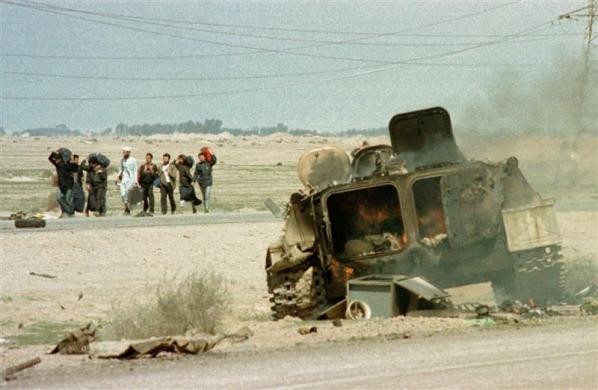 Người Kuwait đi bộ về phía nam, dọc theo quốc lộ Basra, để trở lại Kuwait sau khi Chiến tranh Vùng Vịnh, kết thúc. Bên cạnh đó là một chiếc xe bọc thép của quân đội Iraq bị phá hủy bởi máy bay Mỹ trong khi rút lui khỏi Kuwait ngày 28 tháng 2 năm 1991.