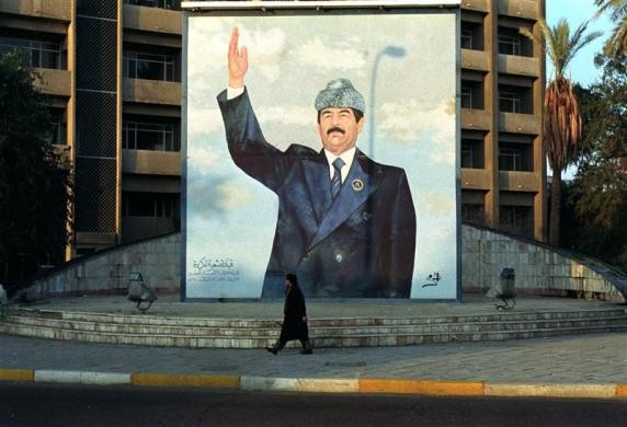 Người dân Iraq đi qua một tấm áp phích hình Tổng thống Saddam Hussein bên ngoài khách sạn Sheraton ở Baghdad, Iraq, ngày 15 tháng 1 năm 1992.
