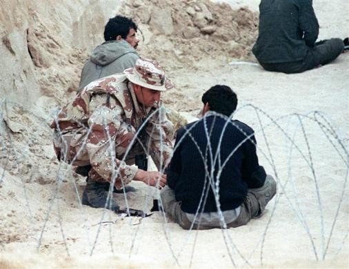 Một lính Hải quân Mỹ ngồi cạnh một tù nhân Iraq bị bắt trong một trận chiến tại giàn khoan dầu ở ngoài khơi Kuwait ngày 19 tháng 1 năm 1991.