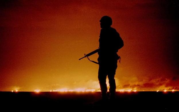 Ảnh chụp ngày 26 tháng 2 năm 1991 ghi lại cảnh một lính Mỹ gác đêm gần một giếng dầu đang bốc cháy ở Kuwait, gần biên giới Iraq vào đêm cuối cùng của cuộc chiến vùng Vịnh. Hàng trăm giếng dầu bị đốt cháy bởi binh sĩ Iraq trước khi họ rút đi.