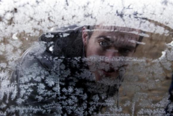 Một thanh niên nhìn qua ô cửa sổ đầy tuyết của tiệm tạp hóa trong làng Prerok, Ferizaj, cách thủ đô Pristina của Kosovo khoảng 40km hôm 24/12.