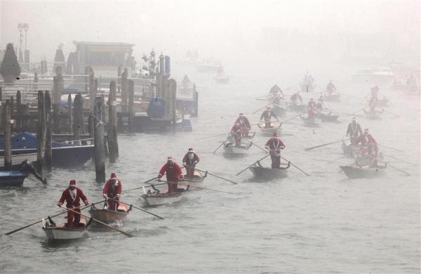 Những người đàn ông mặc trang phục ông già Neol chèo thuyền trên kênh Venice trong sương mù hôm 22/12.