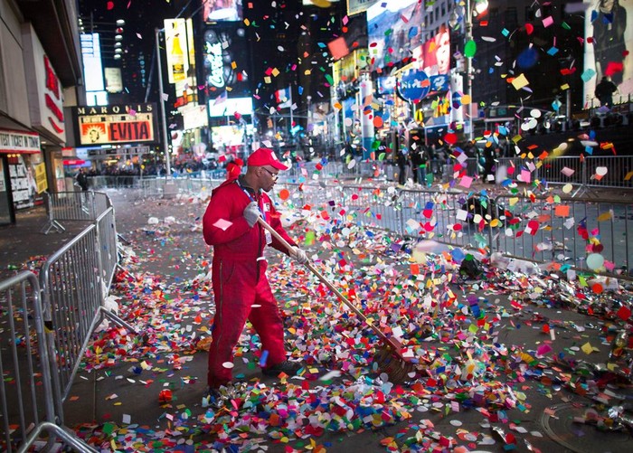 Một lao công quét dọn những mẩu giấy màu tại vỉa hè trên Quảng trường Thời đại, New York sau lễ đón Giao thừa 2013