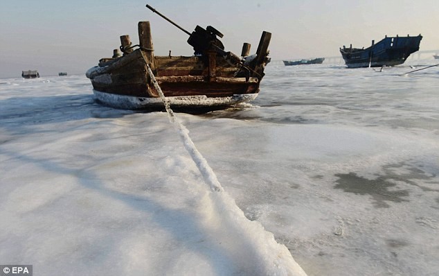 Một chiếc thuyền đánh cá bị mắc kẹt trong băng trên biển của tỉnh Sơn Đông, phía đông Trung Quốc.