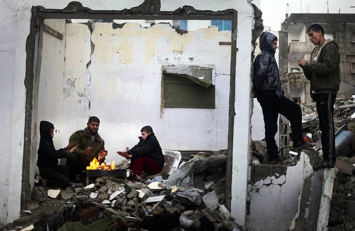 Những người Palestine ngồi sưởi ấm trong một ngôi nhà đổ nát tại thị trấn Beit Lahiya vào ngày 8/1. Những ngôi nhà này đã bị phá hủy trong các trận không kích của Israel.