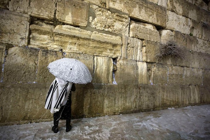 Một người Do Thái cầm cây dù cầm một cây dù phủ đầy tuyết trắng đang cầu nguyện tại Bức Tường phía tây thành phố cổ Jerusalem ngày 10/1. Chỉ qua một đêm, thành phố như bước vào thế giới thần tiên sau khi tuyết rơi dày phủ trắng khắp mọi nơi.