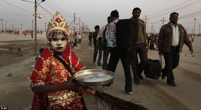 Một bé gái ăn mặc như nữ thần Hindu xin tiền người hành hương.
