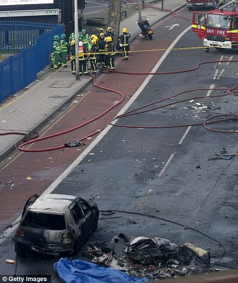 Một chiếc xe hơi bốc cháy vì bị các mảnh vỡ bốc lửa của trực thăng rơi trúng.