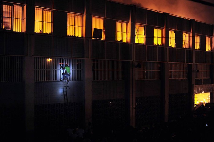 Một người đàn ông cố gắng phá cửa sổ để cứu đồ đạc bên trong tòa nhà đang bốc cháy tại Lome, Togo hôm 11/1.
