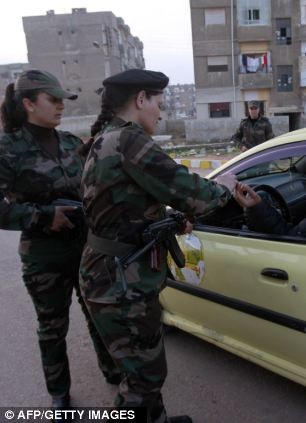 Các nữ binh sĩ Syria kiểm tra một chiếc taxi đi qua trạm kiểm soát của họ.