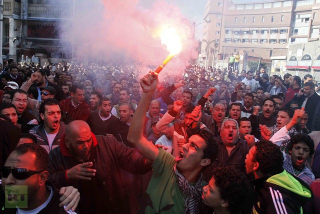 Một người biểu tình Ai Cập và fan hâm mộ câu lạc bộ bóng đá al-Masry giơ cao một ngọn lửa và hô vang khẩu hiệu kêu gọi chính quyền thành phố không chuyển 21 bị cáo tới Cairo để tham dự phiên toà xét xử.