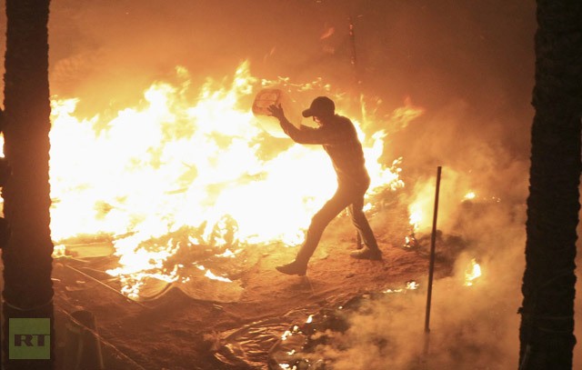 Một người biểu tình cố gắng dập lửa trên chiếc lều bị đốt cháy bởi cảnh sát tại Cairo ngày 25/1.