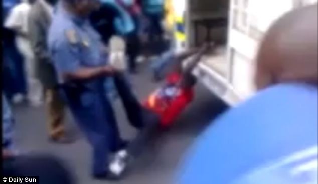 Mido bị buộc lên đuôi xe cảnh sát trước khi bị kéo lê về đồn