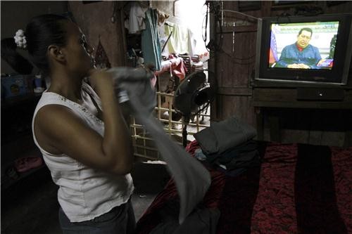 Một phụ nữ đang gấp quần áo khi nghe thông báo Tổng thống qua đời trên truyền hình.