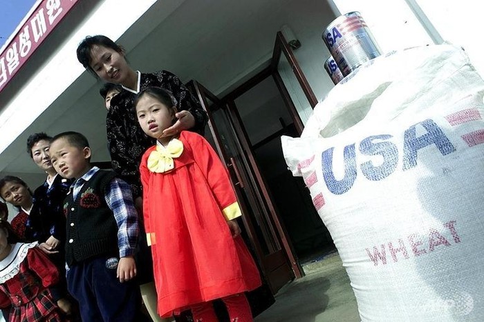 Người dân Triều Tiên bên cạnh lương thực viện trợ của Mỹ.