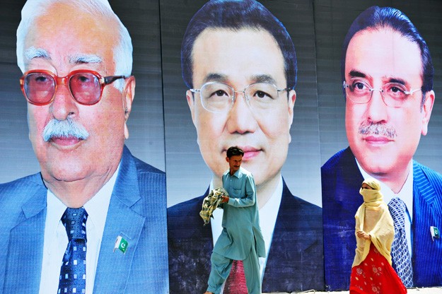 Người đi bộ ngang qua chân dung của Thủ tướng Trung Quốc Lý Khắc Cường (giữa), Tổng thống Pakistan Asif Ali Zardari (phải), và Thủ tướng lâm thời Pakistan Mir Hazar Khan Khoso (trái) ở Rawalpindi.