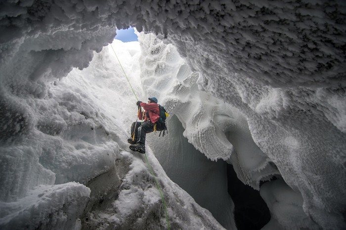 Một nhà khoa học trèo ra khỏi hang động băng được hình thành bởi các miệng núi lửa ở gần đỉnh núi Erebus, Nam Cực.