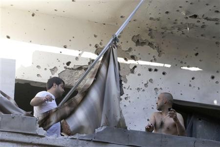 Hai người đàn ông Beirut nhìn vào bức tường loang lổ sau vụ tấn công tên lửa hôm 26/5.