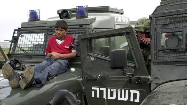 Một trẻ em người Palestine bị buộc vào xe quân sự của quân đội Israel ngăn người dân ném đá vào họ.