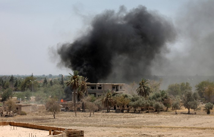 Khói bốc lên từ một tòa nhà sau khi lực lượng đối lập tấn công một trạm kiểm soát của chính phủ tại Deir Ezzor ngày 18/7.
